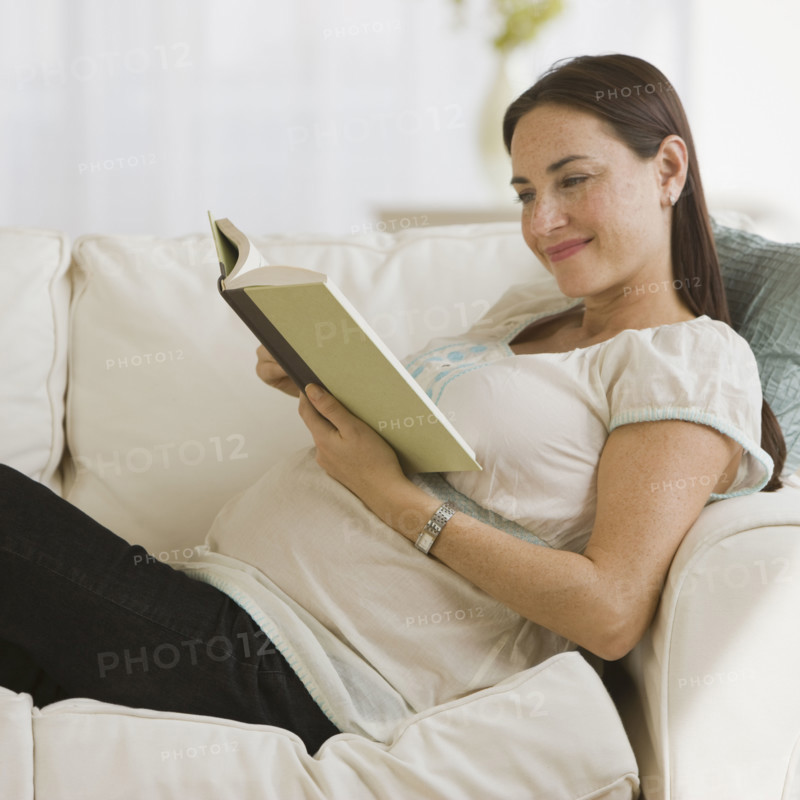 Pregnant Hispanic woman reading book.