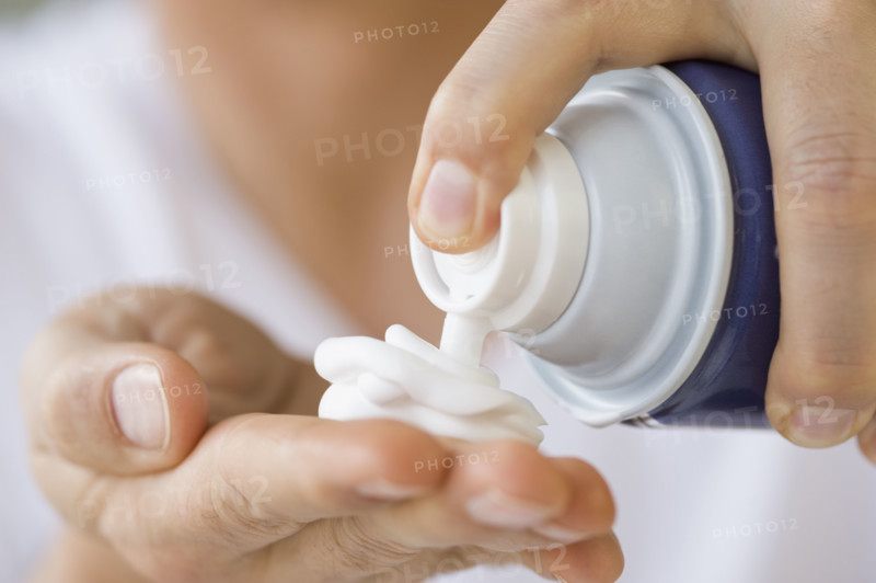 Man dispensing shaving cream into hand.