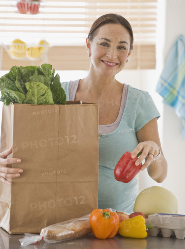 Pregnant Hispanic woman unpacking groceries.