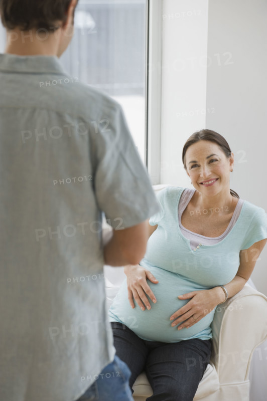 Pregnant Hispanic woman smiling at husband.