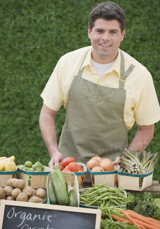 Man next to baskets of vegetables.