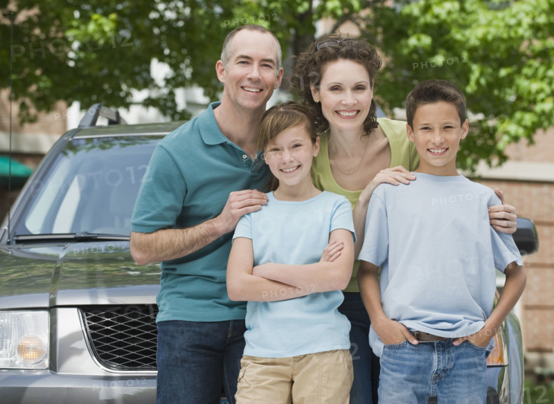 Family with two children in front of car.