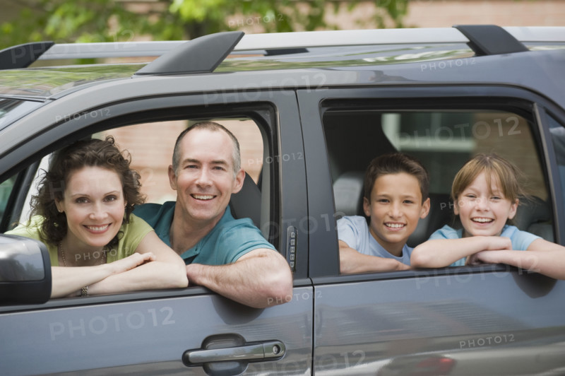 Family with two children looking out car windows.
