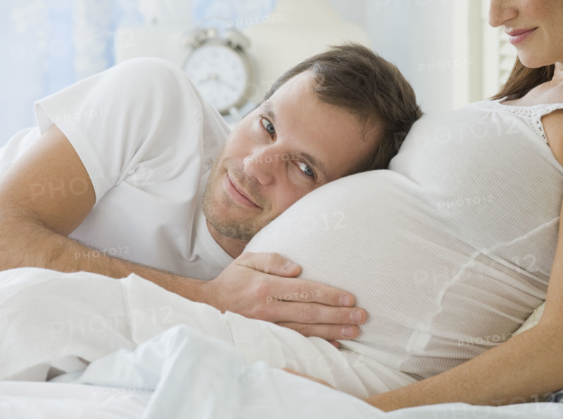Hispanic man resting head on pregnant wife.