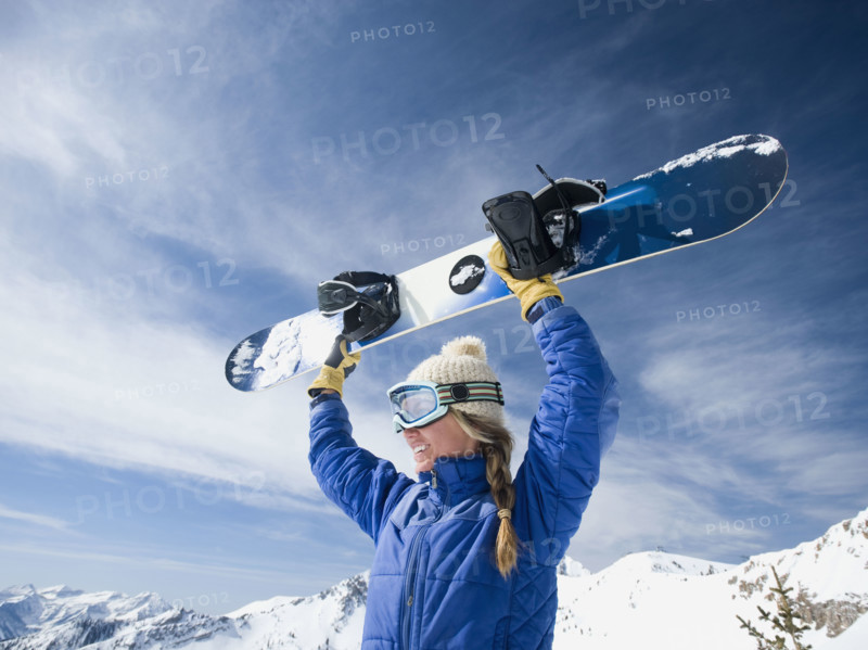 Woman holding snowboard over head. Date : 2008
