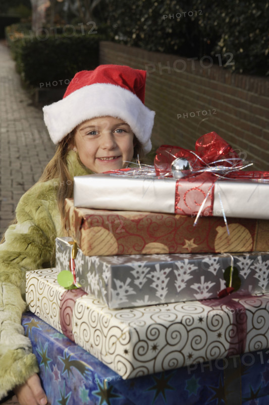Girl holding stack of Christmas gifts. Date : 2008