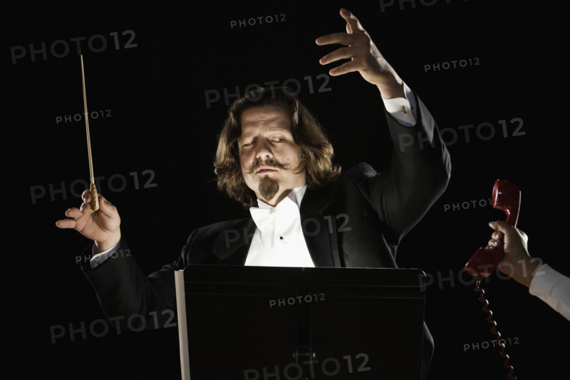 Telephone being handed to orchestral conductor. Date : 2008