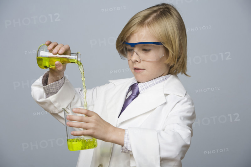 Boy pouring liquid into beaker. Date : 2008