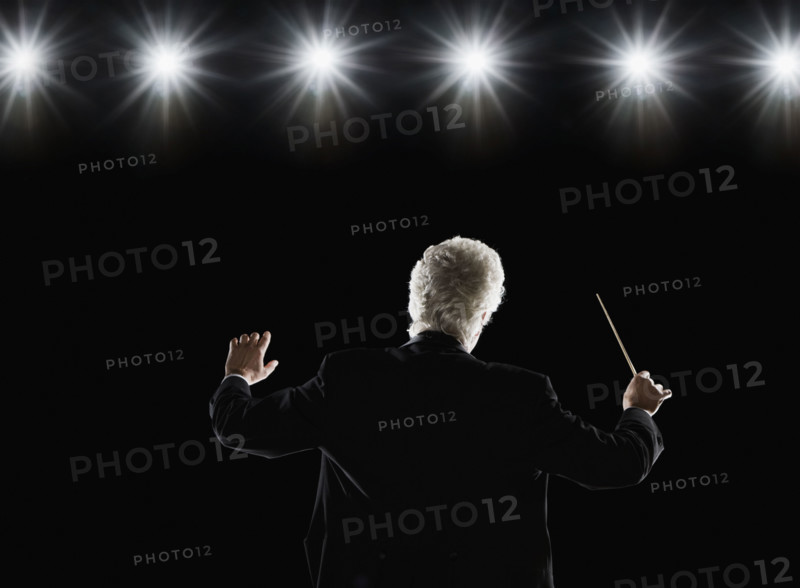 Man in tuxedo conducting under lights. Date : 2008
