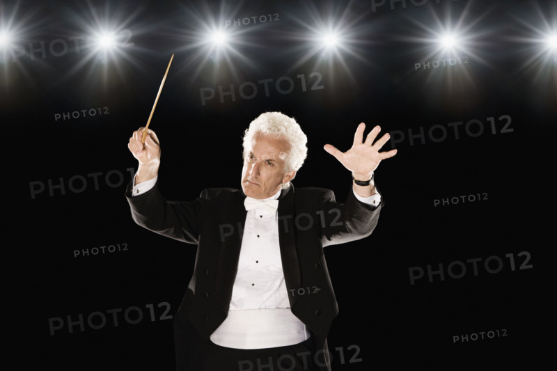 Man in tuxedo conducting under lights. Date : 2008