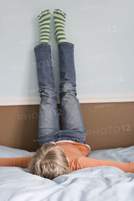 Girl laying on bed with feet on wall. Date : 2008