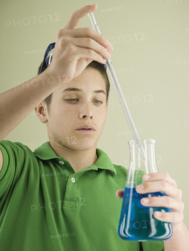 Boy measuring liquid in beaker. Date : 2008