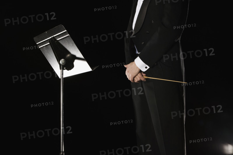 Male conductor standing next to music stand. Date : 2008