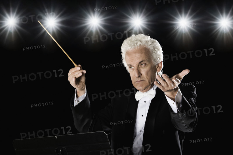 Man in tuxedo conducting under lights. Date : 2008