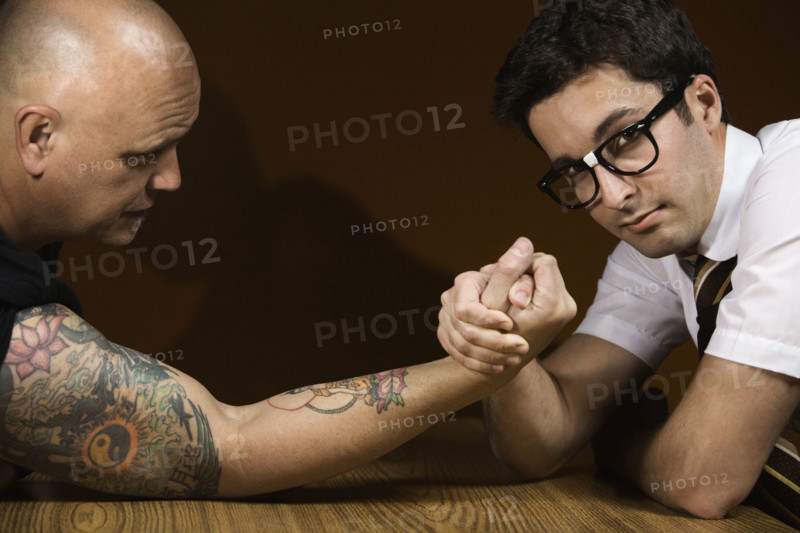 Nerdy man arm wrestling tattooed man. Date : 2008