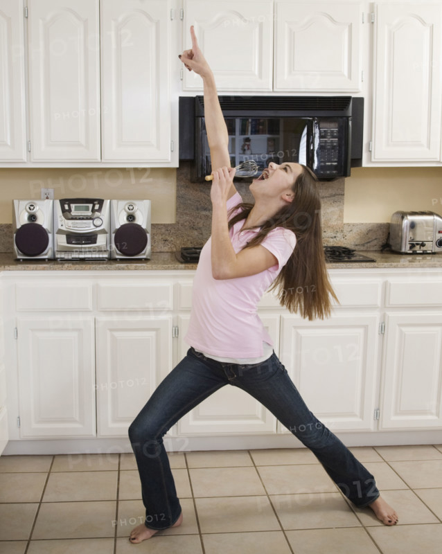 Teenaged girl singing in kitchen