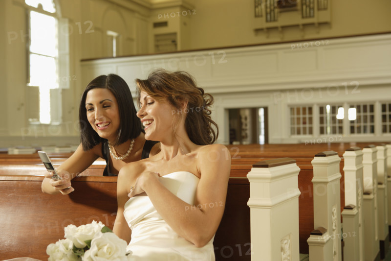 Bride and friend looking at cell phone. Date : 2008