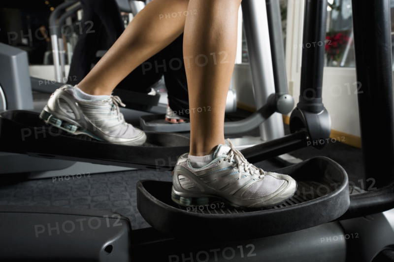 Woman exercising on elliptical machine. Date : 2008