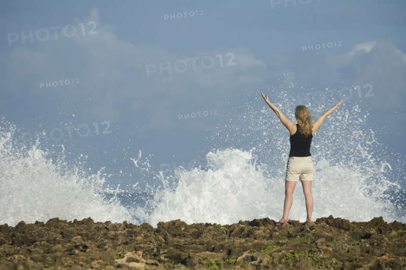Woman with arms raised in front of ocean, Oahu, Hawaii, United States. Date : 2008