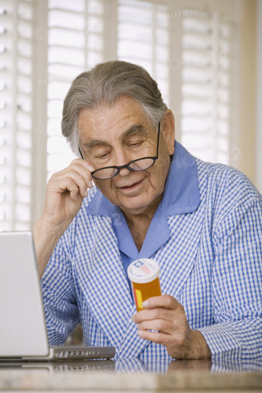 Senior man reading medication bottle. Date : 2008