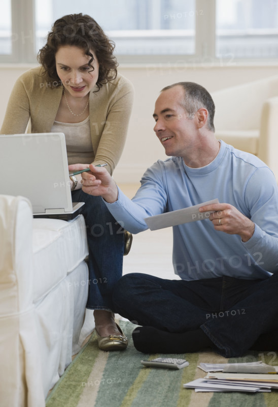 Couple paying bills online at home.