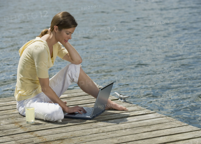 Woman using laptop on dock.