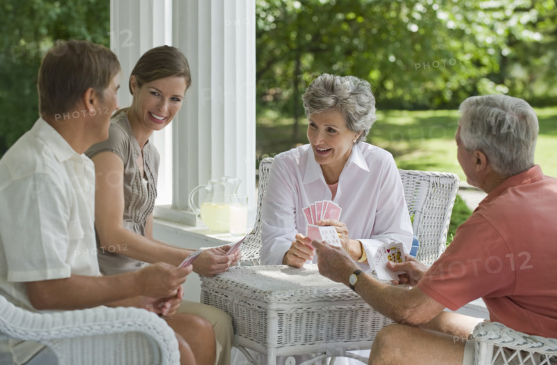 Couples playing card game on porch.