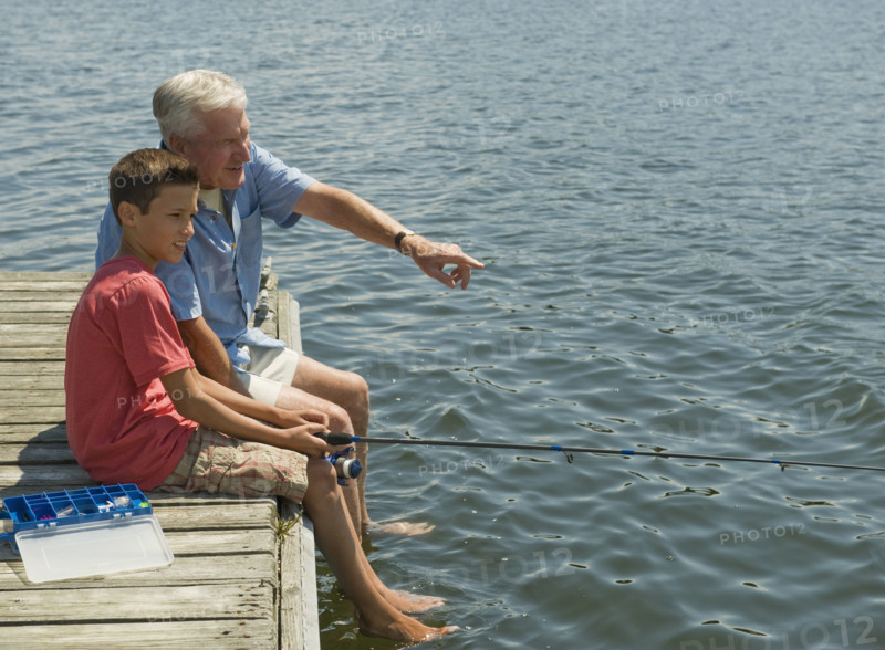Grandfather and grandson fishing off dock.