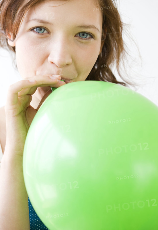 Teenage girl blowing up balloon. Date : 2008