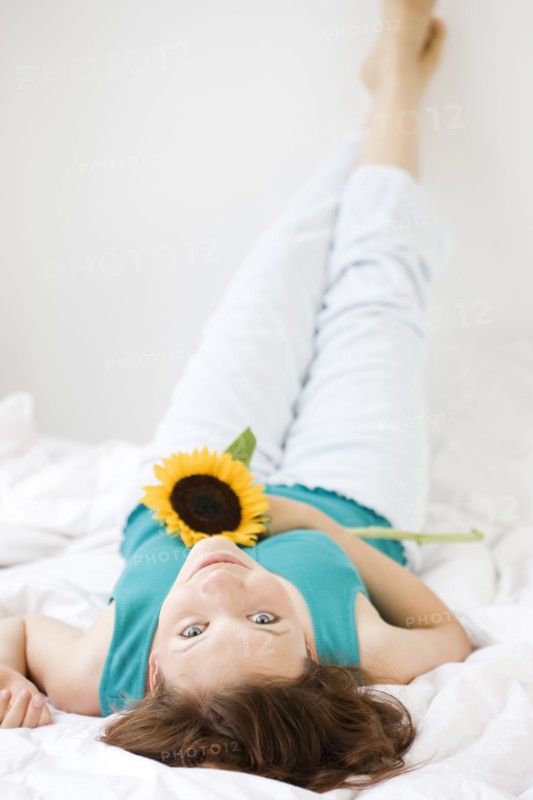 Teenage girl holding flower in bed. Date : 2008