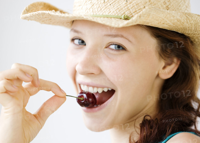 Teenage girl in cowboy hat eating cherry. Date : 2008