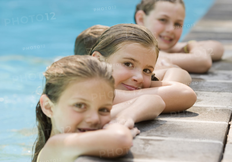 Girls in a row leaning on edge of swimming pool. Date : 2008