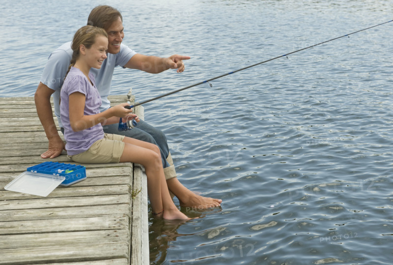Father and daughter fishing off dock.