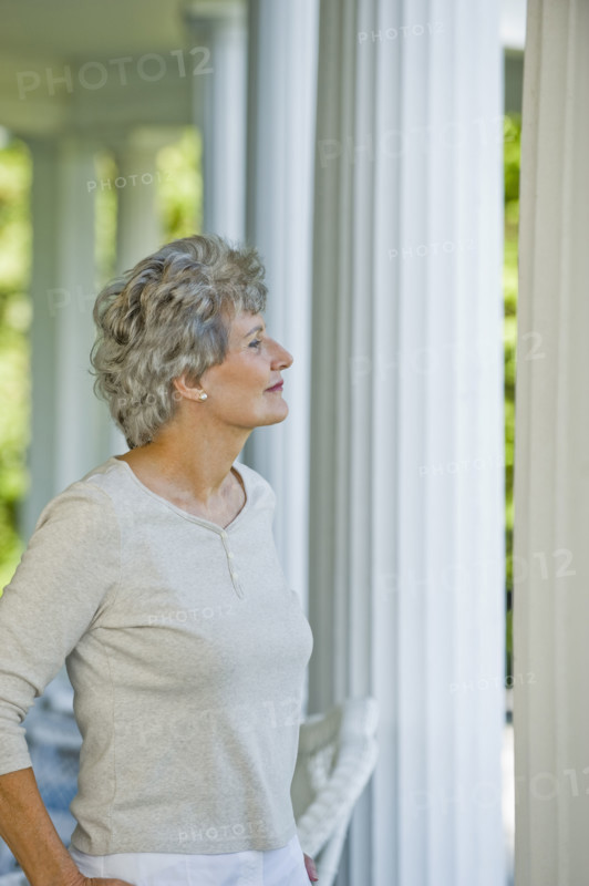 Senior woman standing on porch.