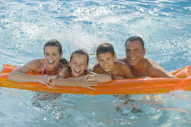 Family resting on raft in swimming pool.