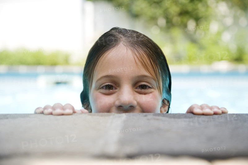 Girl peeking over edge of swimming pool. Date : 2008