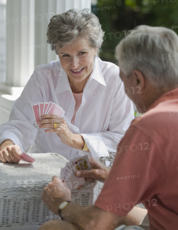 Senior couple playing card game on porch.