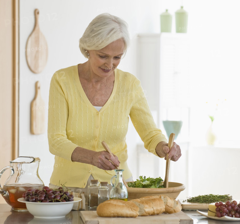Senior woman tossing salad.
