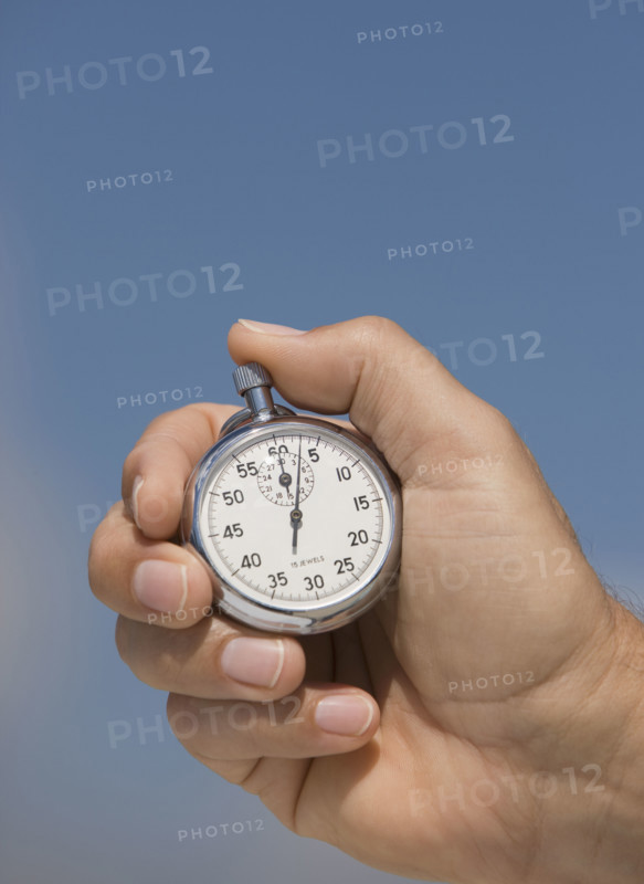 Close up of hand holding stopwatch.