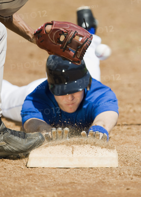 Baseball player sliding into home base.