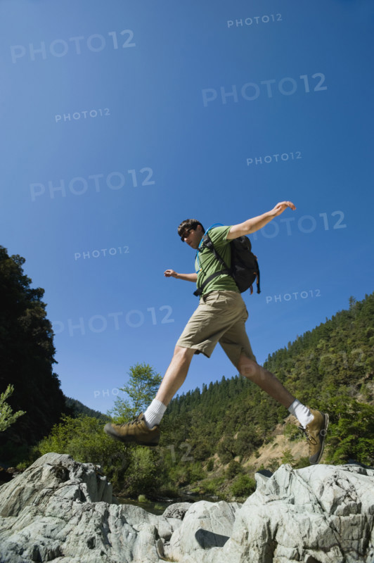 Hiker jumping across rocks. Date : 2008