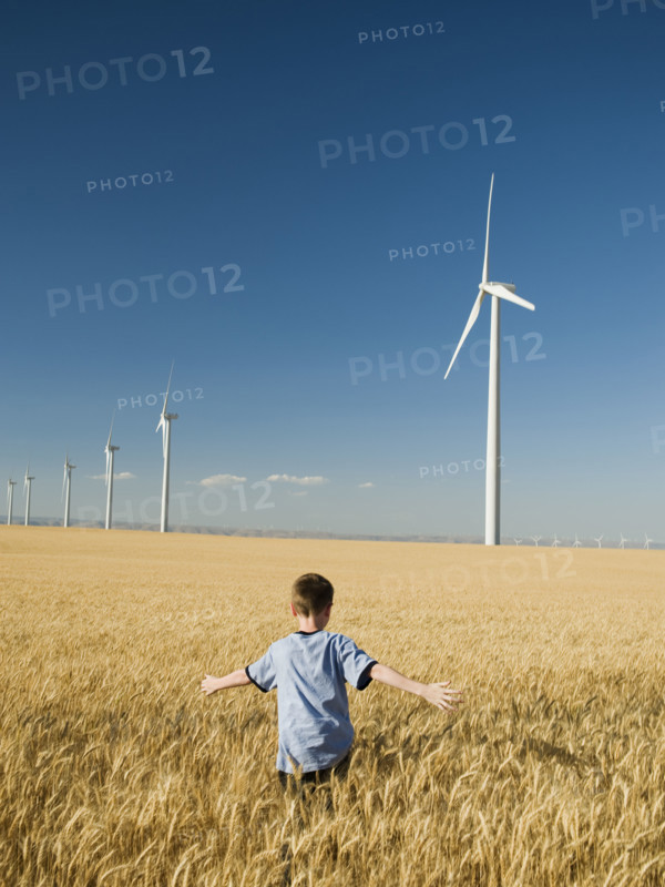 Boy running through field on wind farm. Date : 2008