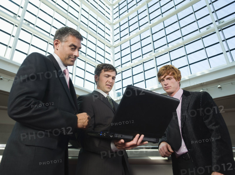 Businessmen looking at laptop in convention center atrium. Date : 2008