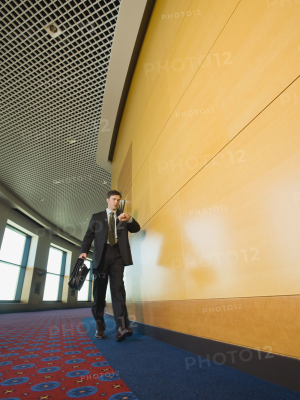 Businessman checking watch in corridor. Date : 2008