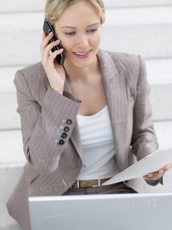 Businesswoman working on laptop and talking on cell phone. Date : 2008