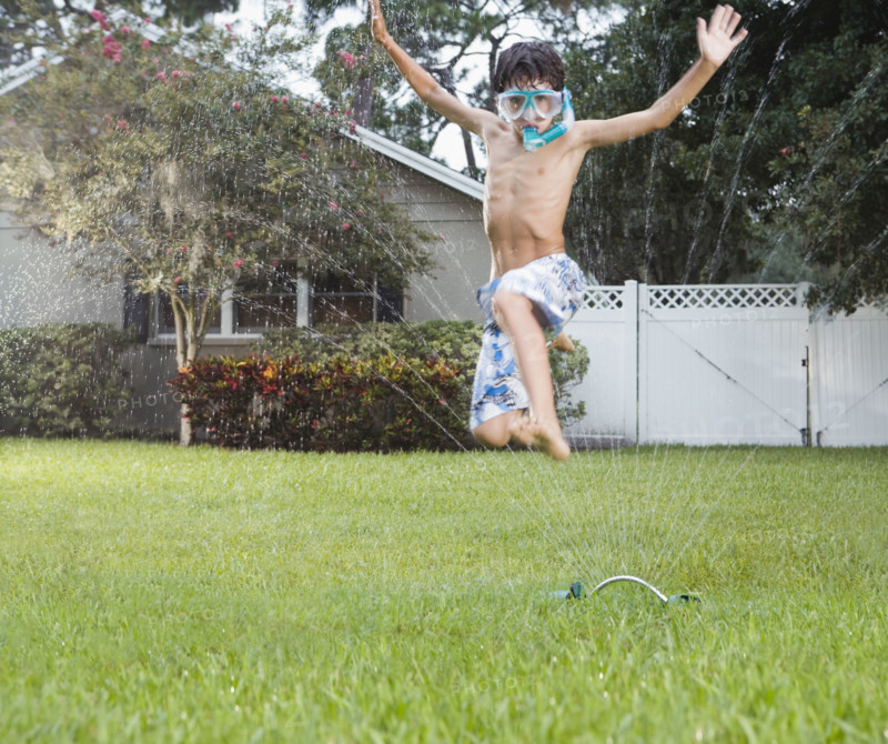 Boy jumping through sprinkler. Date : 2008