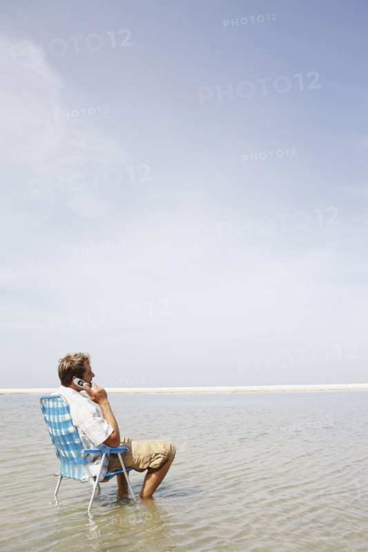 Man talking on cell phone in middle of water. Date : 2008