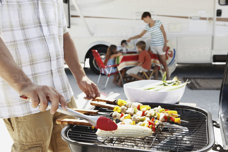 Man grilling dinner for family on beach. Date : 2008