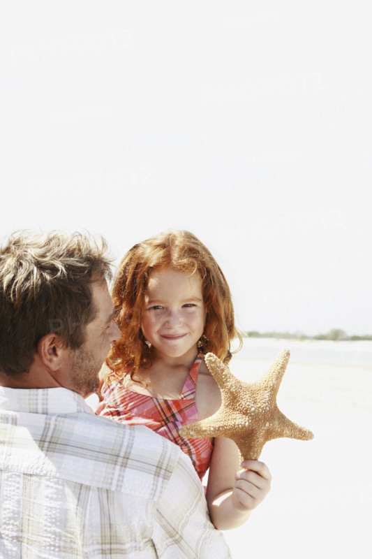 Father carrying daughter and starfish. Date : 2008