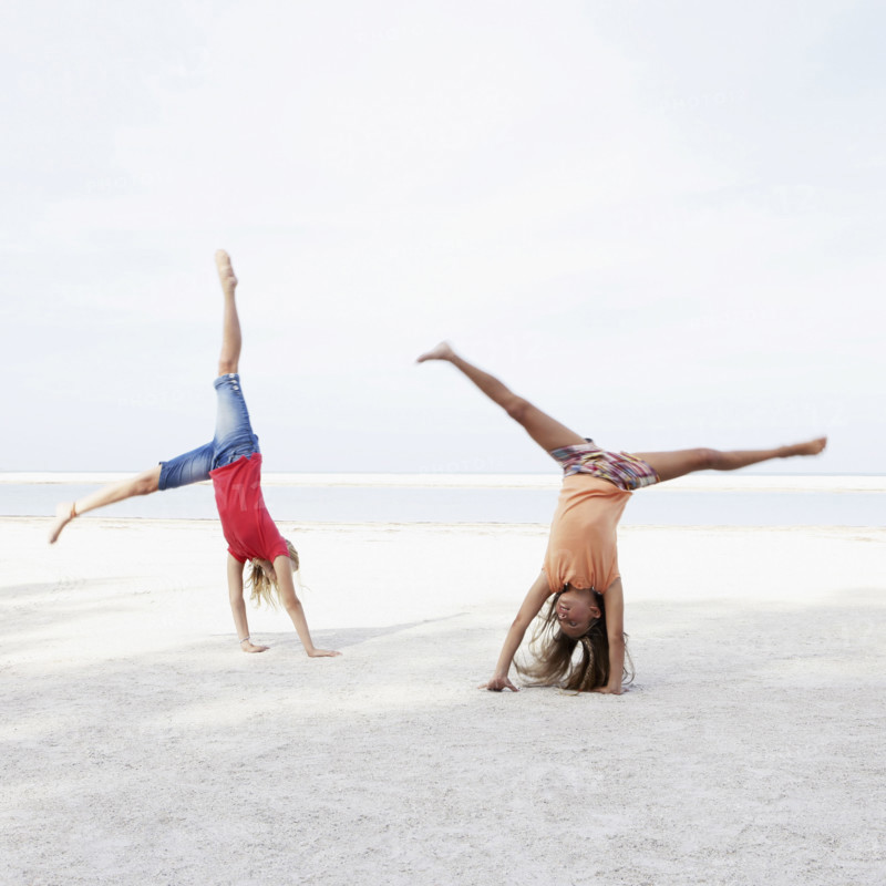 Girls doing cartwheels on beach. Date : 2008
